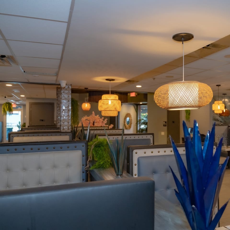 Interior of Casa Patron Mexican Kitchen with booth seating, woven pendant lights, and agave plant decor.