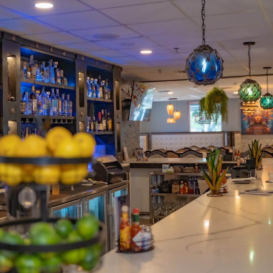 Interior of Casa Patron Mexican Kitchen bar area with blue-lit liquor shelves and colorful hanging lights.