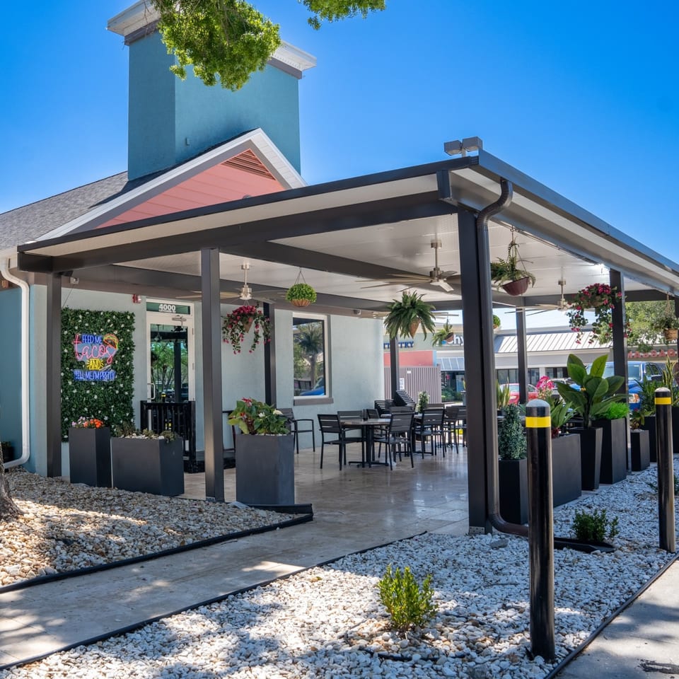 Casa Patron Mexican Kitchen's outdoor patio with tables, chairs, plants, and a neon sign.